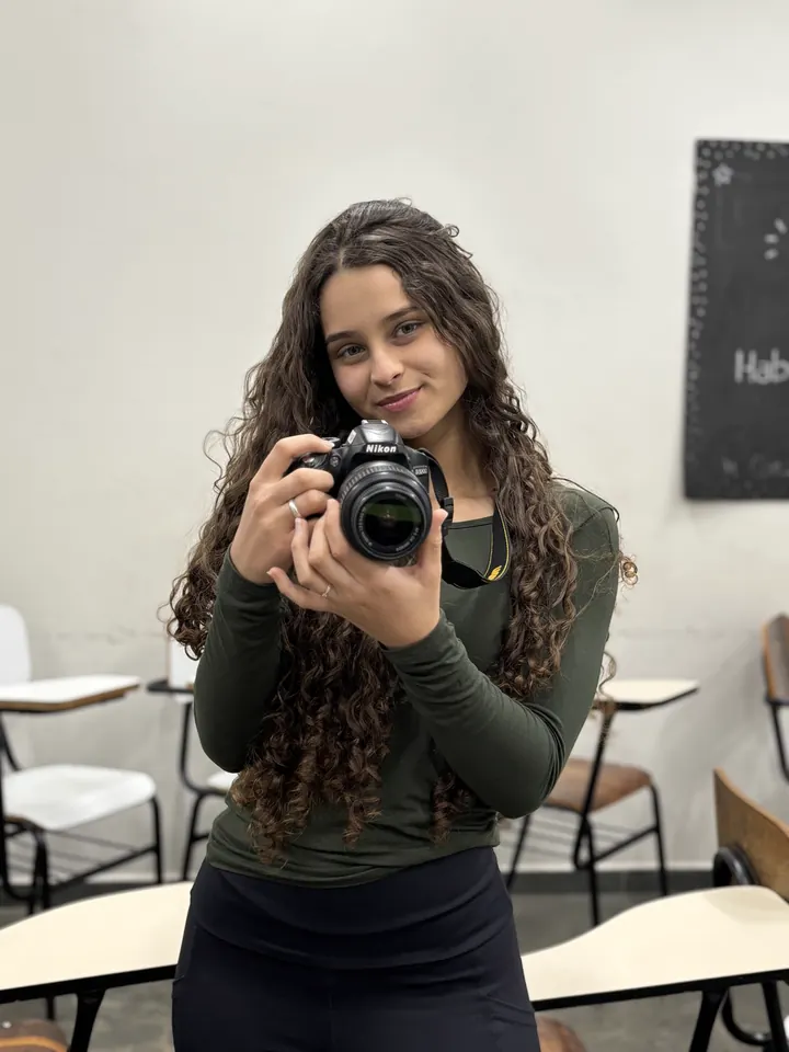 Maria Eduarda Pacheco segurando uma câmera fotográfica